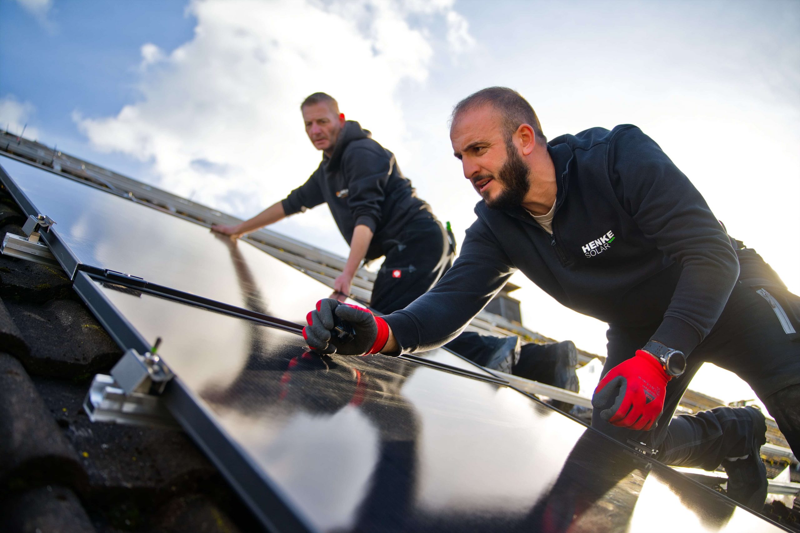 Mitarbeitende der Henke Solar installieren PV-Module auf einem Dach.
